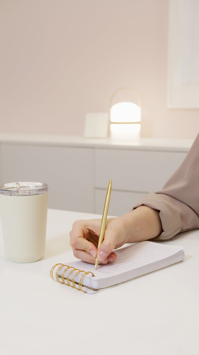 A Person Writing on a Small Notebook